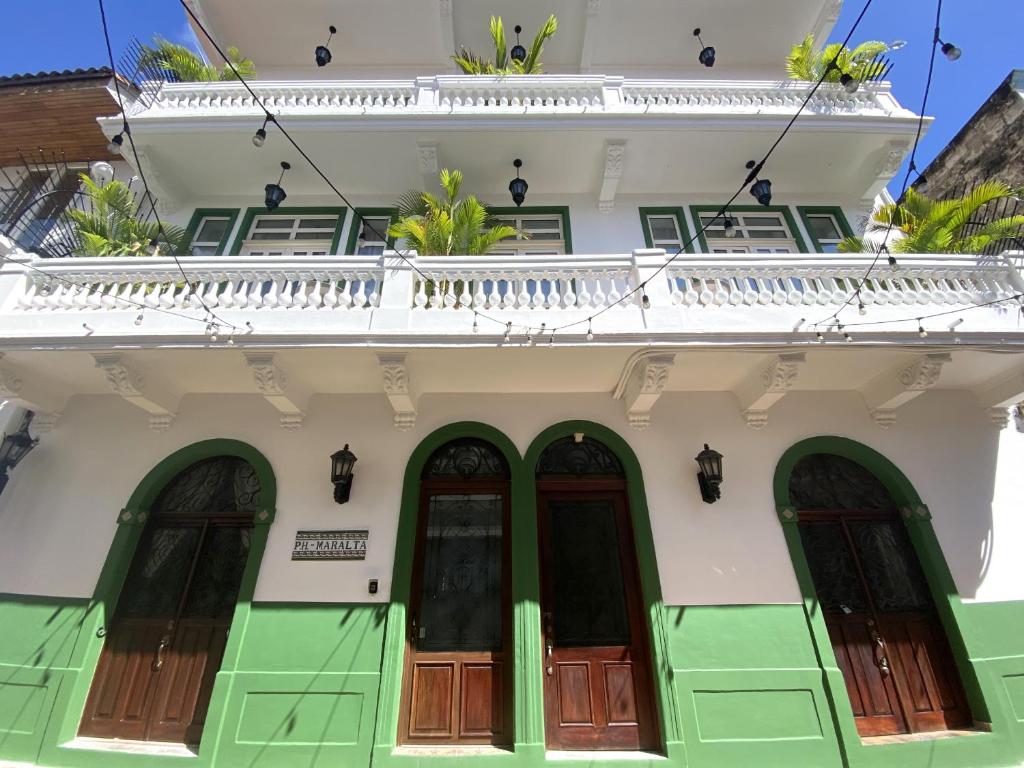 a white building with green doors and a balcony at AmazINN Places Rooftop and Jacuzzi II in Panama City