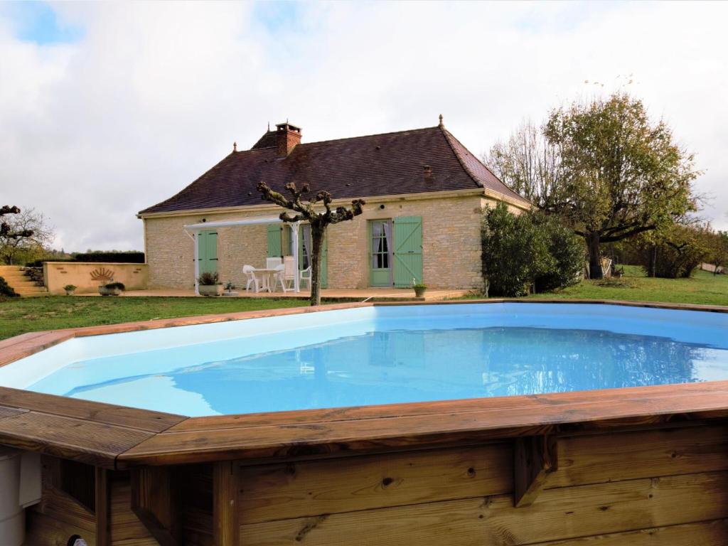einem großen Pool mit Holzterrasse und einem Haus in der Unterkunft Cosy holiday home with swimming pool in Lavercantière