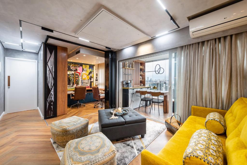 ein Wohnzimmer mit einem gelben Sofa und einem Tisch in der Unterkunft Riverone 23o Andar - Apartamento Ultra Moderno de Luxo 2 Dorm + 2 Banheiros piscina borda infinita in São Paulo