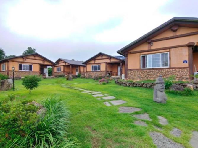 a yard of a house with a stone path at Geumok Log Pension in Seogwipo