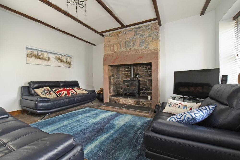 a living room with two leather couches and a fireplace at Beach Retreat in Seahouses