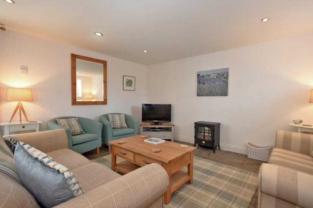 a living room with couches and a television and a table at Croft Cottage Alnwick in Alnwick