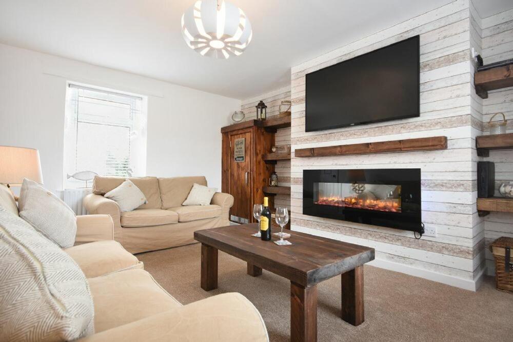 a living room with a fireplace with a flat screen tv at Rivershield in Warkworth