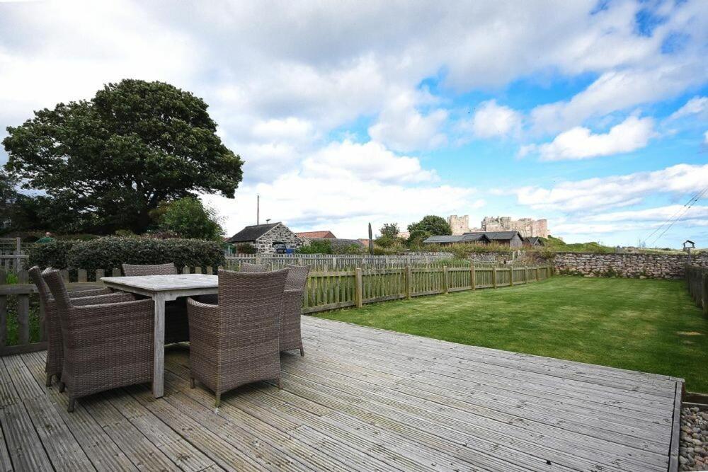 a wooden deck with a table and chairs on a yard at Dunford Cottage in Bamburgh