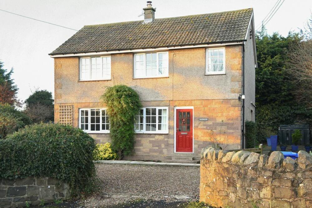 a brick house with a red door at Barmoor in Embleton