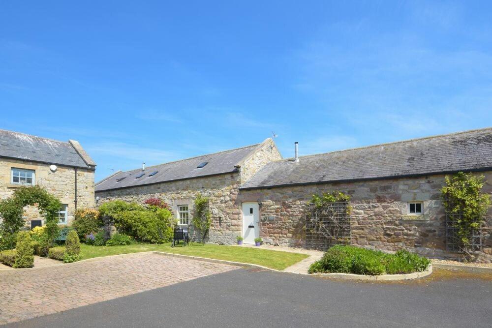 an old stone house with a road in front of it at Lavender Cottage Village Farm in Seahouses