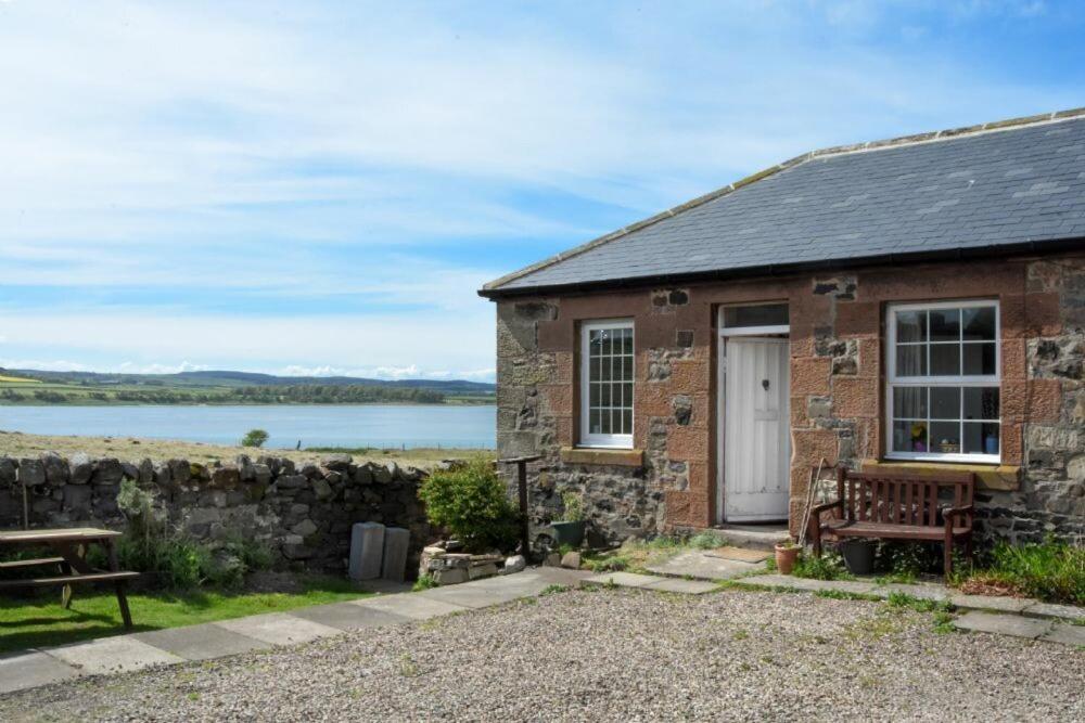 um chalé de pedra com um banco e uma mesa em Kittiwake Cottage, Budle Bay em Bamburgh