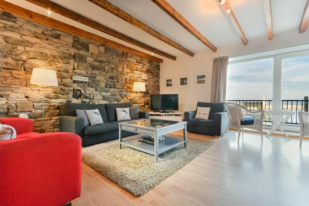 a living room with a stone wall and a table at Farne Lookout in Seahouses