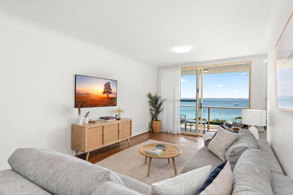 a living room with a couch and a view of the ocean at South Pacific Unit 5 13 Shoal Bay Road in Shoal Bay
