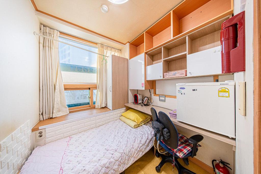 a small bedroom with a bed and a refrigerator at Dream Single House in Seoul