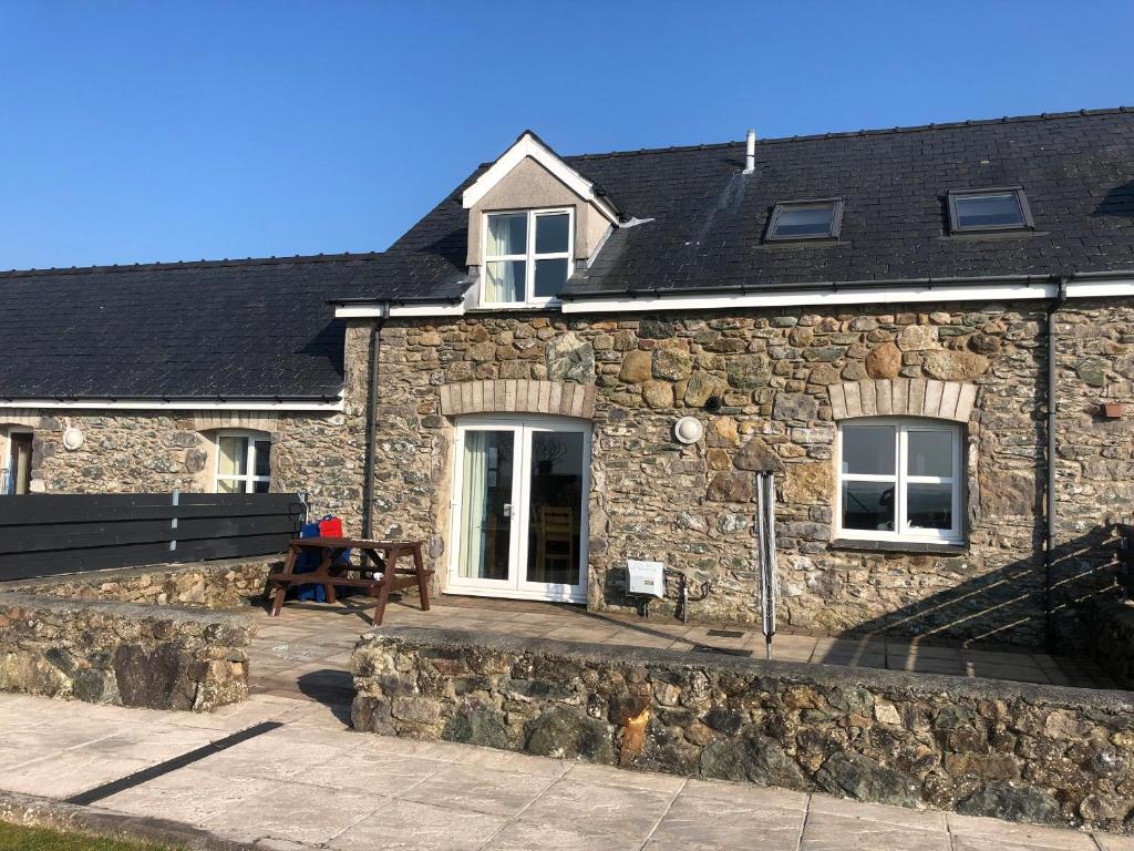 una casa de piedra con un banco delante en Drosgl, en Llangefni