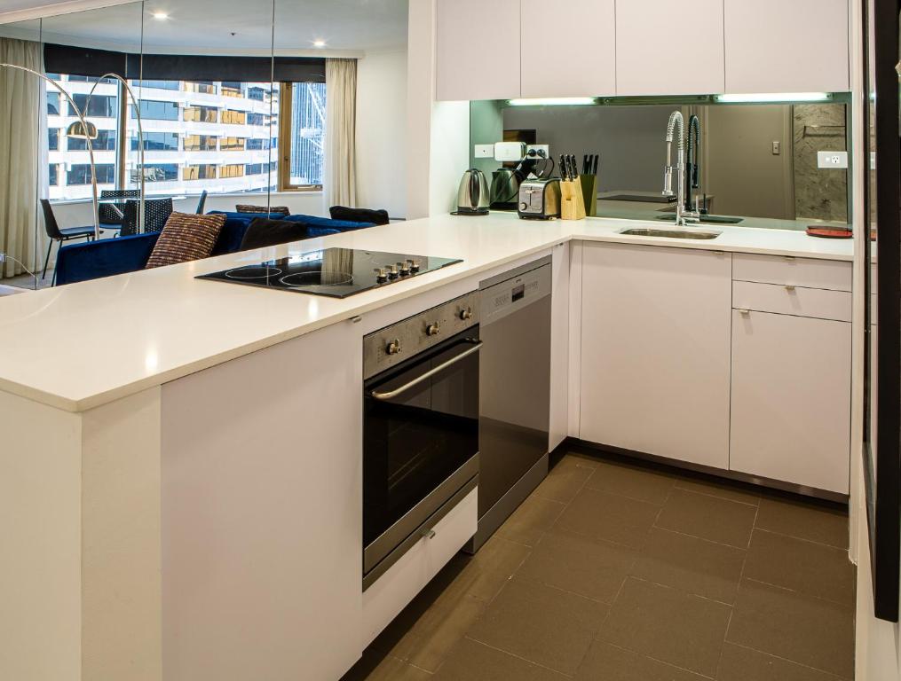 een keuken met witte kasten en een fornuis met oven bij Quay West 1301 Self- Catering in Sydney