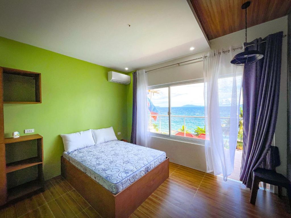 ein Schlafzimmer mit einem Bett und einem großen Fenster in der Unterkunft Anilao Ocean View Guest House in Mabini