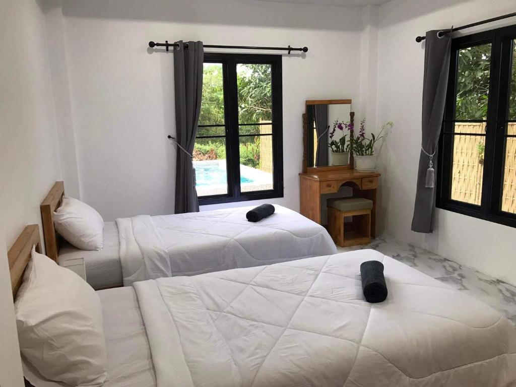 a bedroom with two beds and a window at Villa MILTONIA in Ban Ai Dao