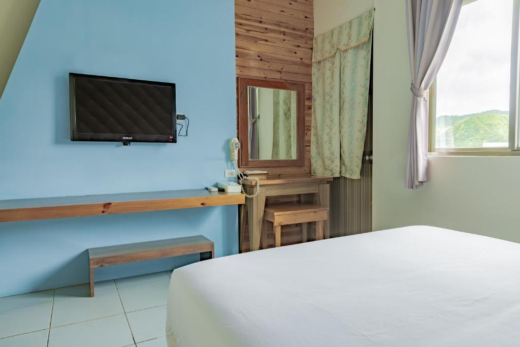 a bedroom with a bed and a tv on a wall at Star-Moon B&amp;B Green Island in Green Island