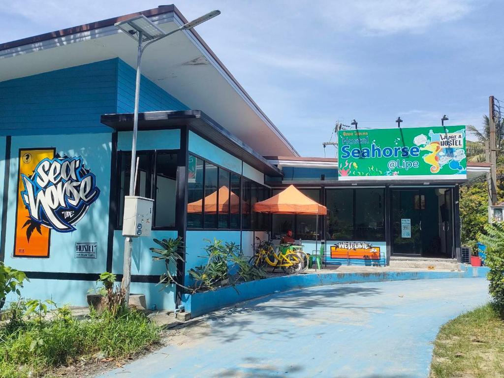 een blauw gebouw met een bord ervoor bij Seahorse Lipe Hostel in Ko Lipe