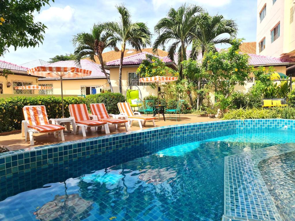 a swimming pool with chaise lounge chairs next to a house at BUTTERFLY GARDEN BOUTIQUE RESIDENCES Apts and villas, A Lifestyle Destination Ex Lg 1-3 bedroom units , Full kitchen, 2 Full bathrooms, Rain shower, Spa bath, FREE BBQ, Free fast fiber optic WIFI, Staff 24-7 in Pattaya South