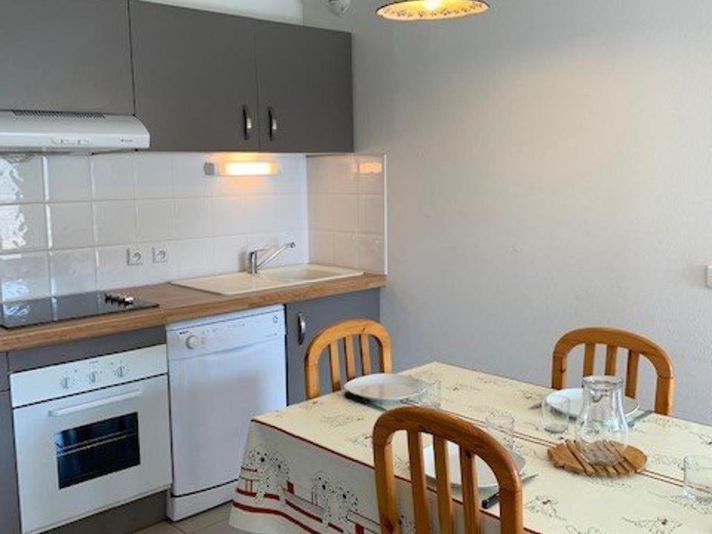 - une cuisine avec une table, des chaises et un évier dans l'établissement Appartement F3 avec balcon & terrasse, proche plage, 6 couchages - Narbonne Plage - FR-1-229B-23, à Narbonne