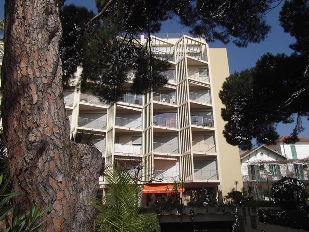 a tall white building with a tree in front of it at Appartement Le Lavandou, 2 pièces, 4 personnes - FR-1-308-13 in Le Lavandou