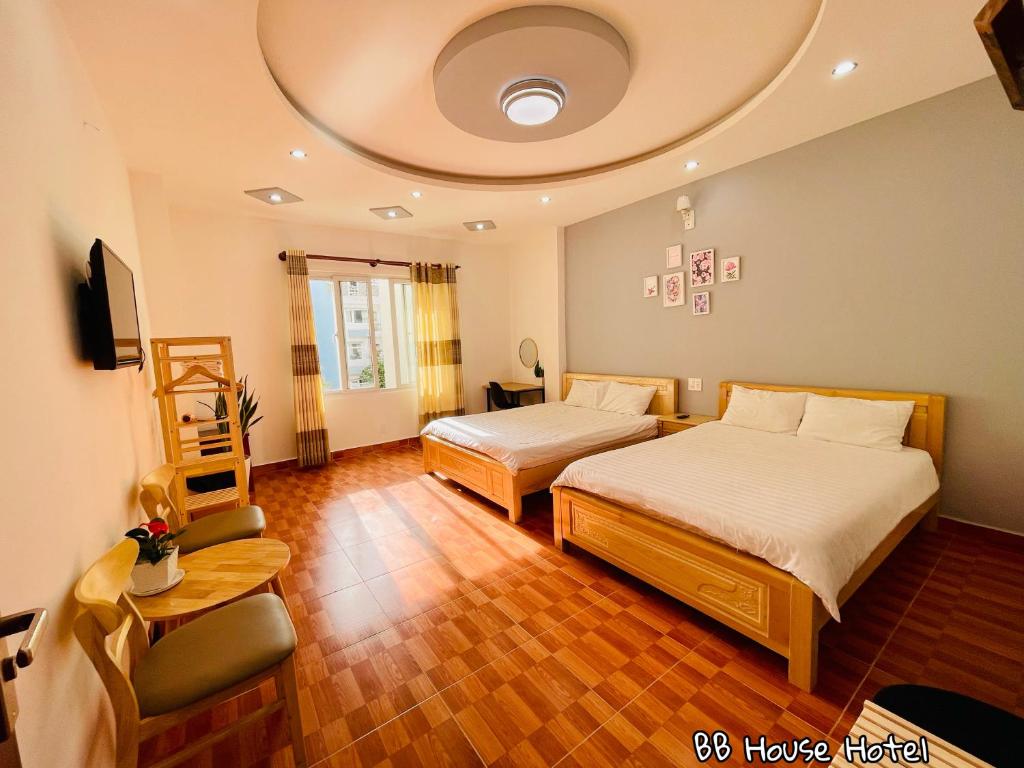 a hotel room with two beds and a chair at BB House Hotel Đ&agrave; Lạt in Da Lat