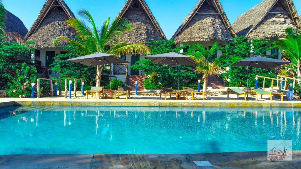 a resort with a swimming pool with chairs and umbrellas at Jabali Bungalows Lodge in Paje