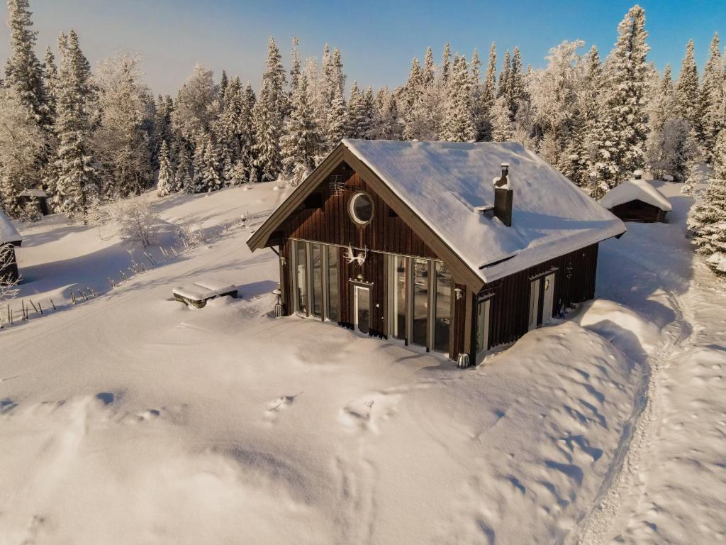 a cabin covered in snow with trees in the background at Ottsjö-Åre Lodge in Ottsjö