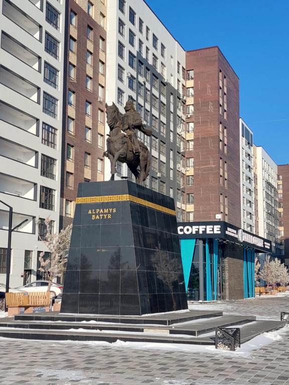 een standbeeld in het midden van een stad met gebouwen bij Отличная квартира ЖК Алпамыс in Astana