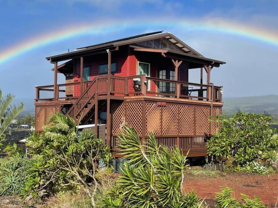 a house with a rainbow in the sky at COZY OFF GRID LAVA HOME - 2 Stories, Ocean View in Pahoa