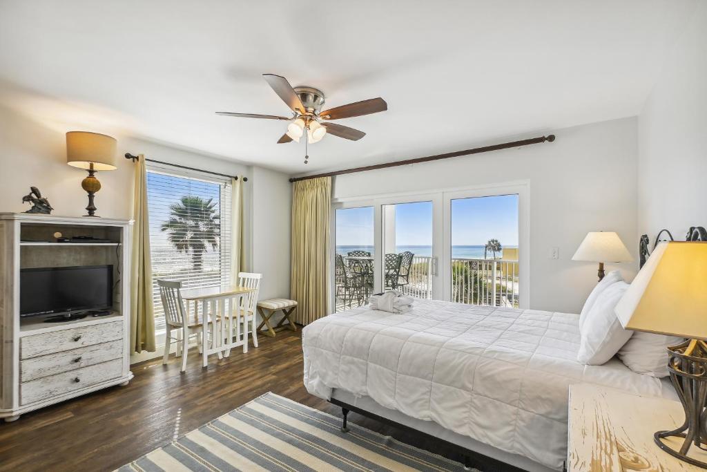 1 dormitorio con cama, TV y balcón en SeaCrest 301A condo, en Fort Walton Beach