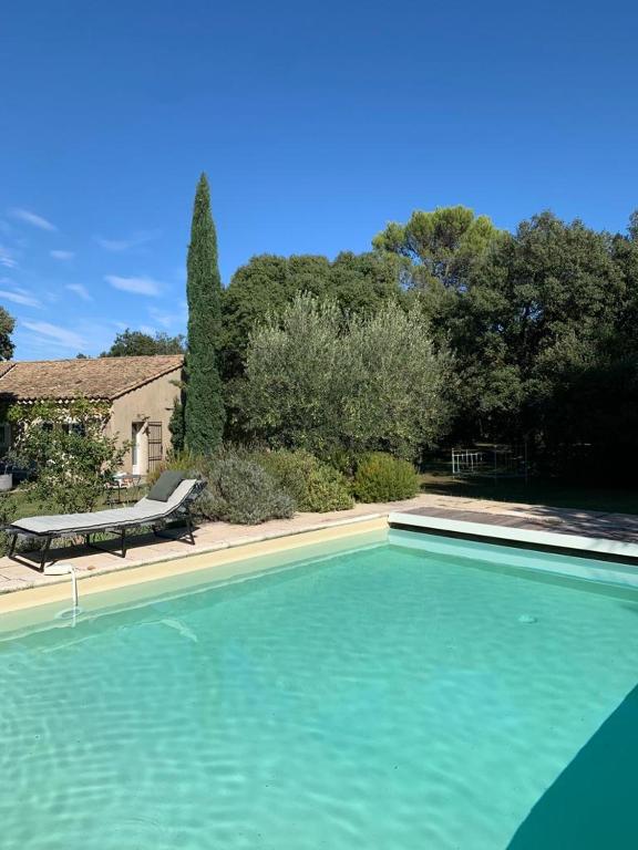 une piscine avec un banc à côté d'une maison dans l'établissement Maison Les Chênes, à Eygalières