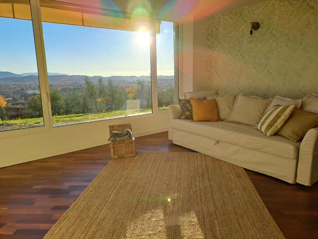 a living room with a couch and a large window at Aria di Franciacorta in Corte Franca
