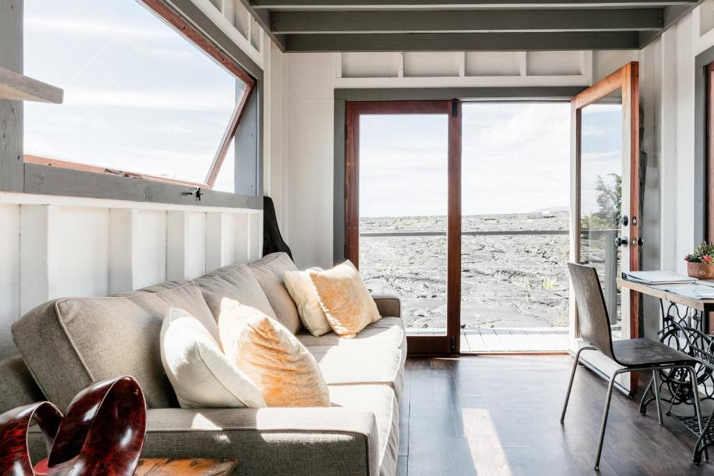 a living room with a couch and a table at THE PHOENIX HOUSE - EPIC Tiny Home Gem on Volcanic Lava Field! in Kehena