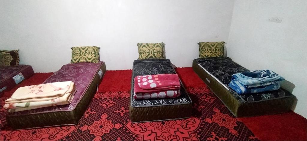 3 camas sentadas en una habitación con alfombra roja en Gite taouraout, en Midelt