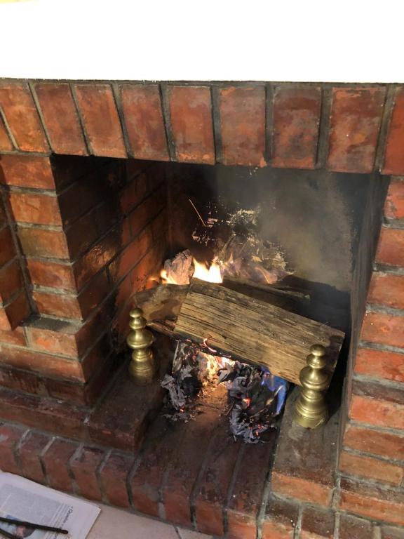 a brick fireplace with a fire in it at La plage au bout du jardin &#47; Sword Beach cottage in Hermanville-sur-Mer