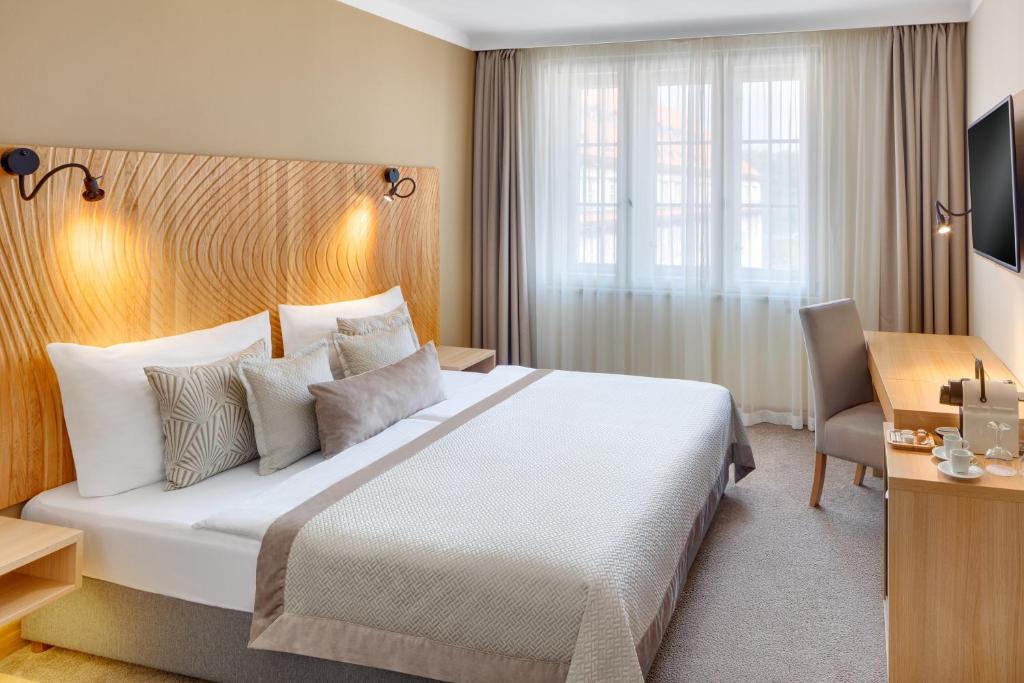 Pokój hotelowy z dużym łóżkiem i biurkiem w obiekcie Hotel Clement w Pradze