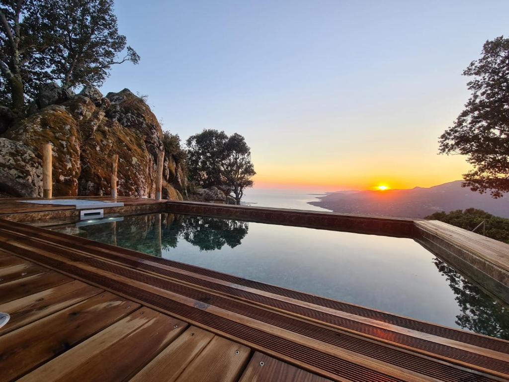 une piscine à débordement avec un coucher de soleil en arrière-plan dans l'établissement A VIGNA - CASEDDU A PUNTA vue mer et piscine, à Viggianello