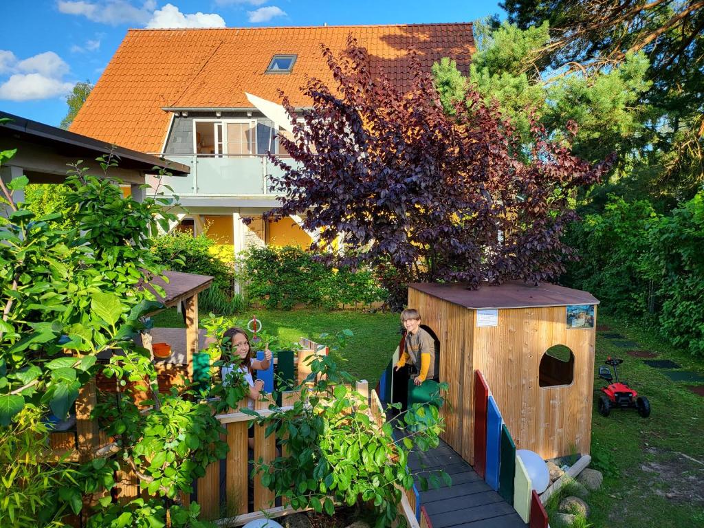 a group of people standing in a garden with a play house at Ferienhaus Strandstr 29 in Kolpinsee