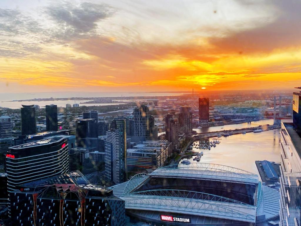 Melbourne CBD Apt with Free Car Park Ocean View في ملبورن: إطلالة على أفق المدينة مع غروب الشمس