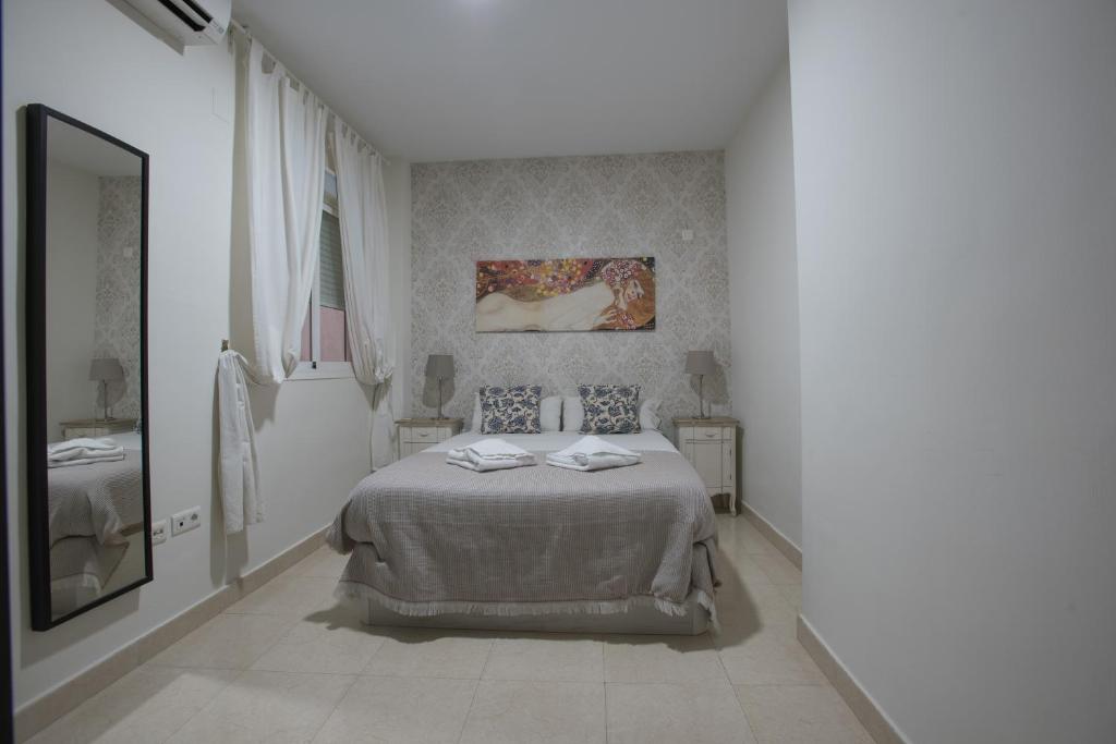 Habitación blanca con cama y espejo en Carreteria 73 Malaga Center, en Málaga