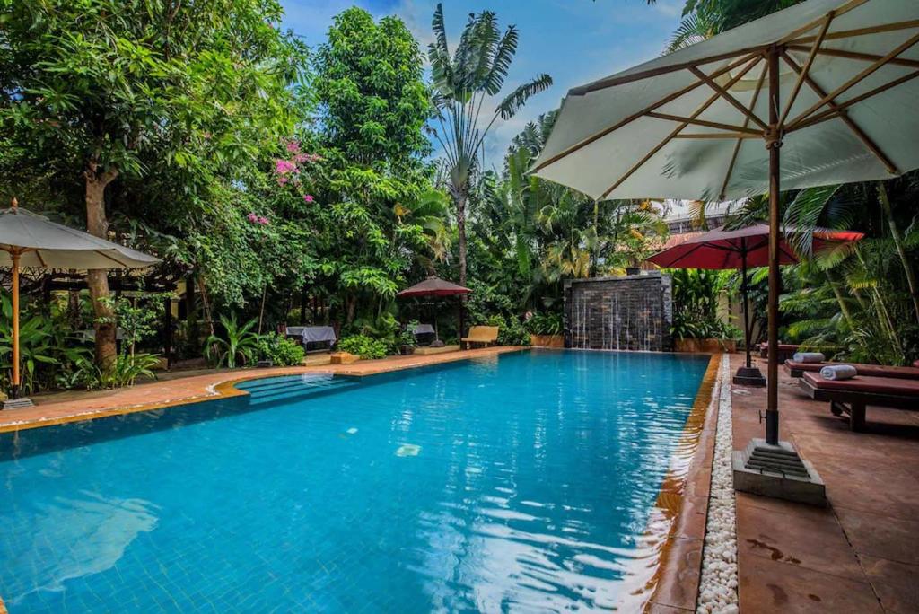 a swimming pool with an umbrella and chairs and tables at Marirath Boutique Hotel in Siem Reap