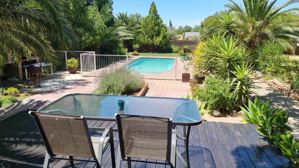 een tafel en stoelen op een terras met een zwembad bij Spandau Manor in Graaff-Reinet