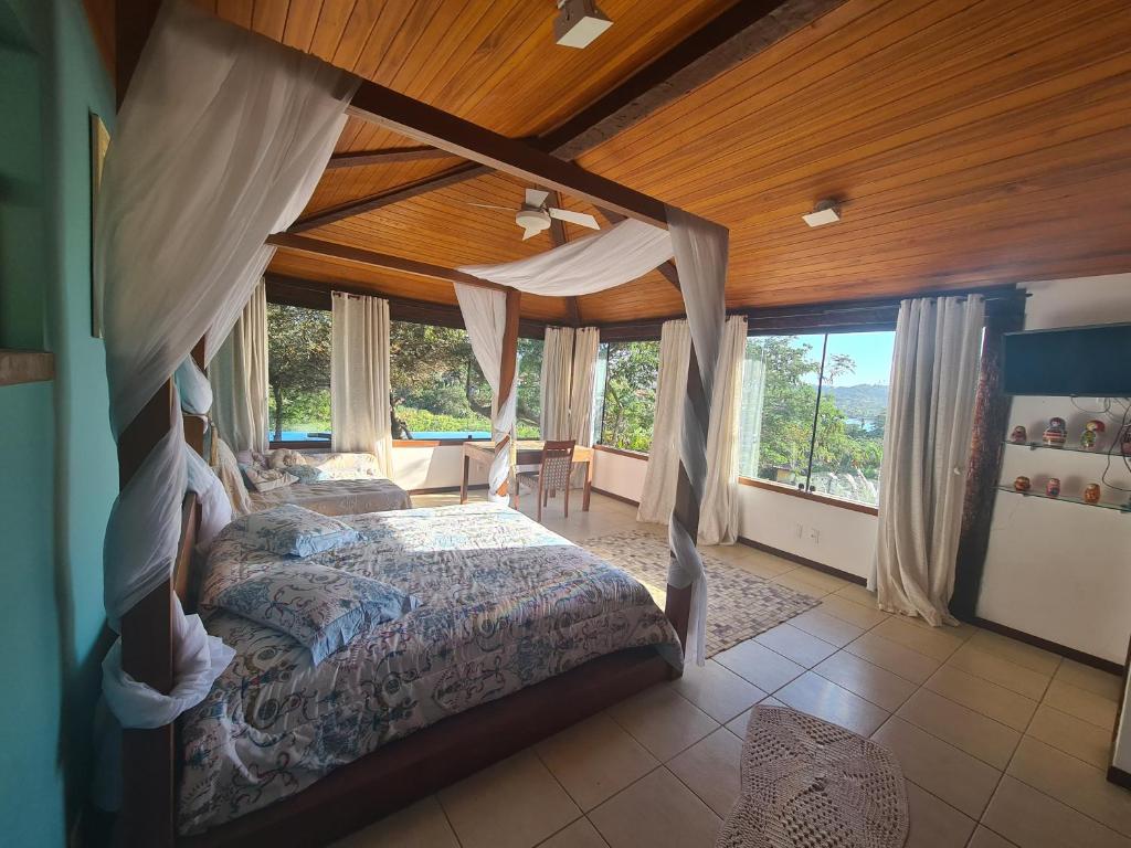1 dormitorio con cama con dosel en una habitación con ventanas en Casa Ferradura com hidro,piscina e 500 metros da praia, en Búzios