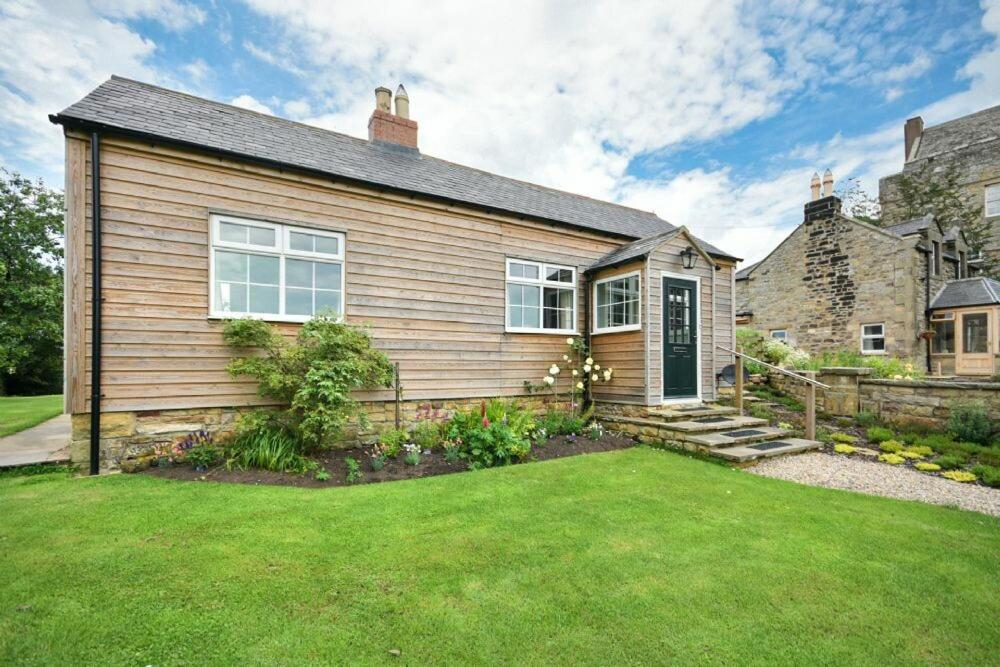 a house with a green lawn in front of it at Rose Cottage Elsdon in Elsdon