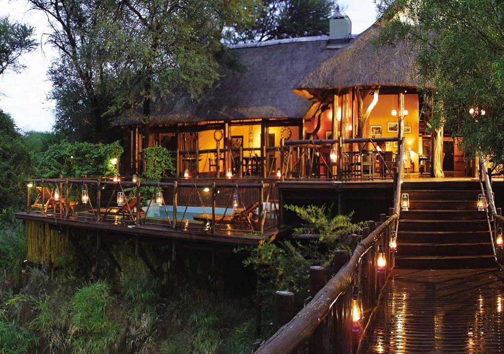 Madikwe River Lodge by Dream Resorts في محميّة ماديكوي الطبيعيّة للطرائد: منزل به سقف من القش والدرج اليه