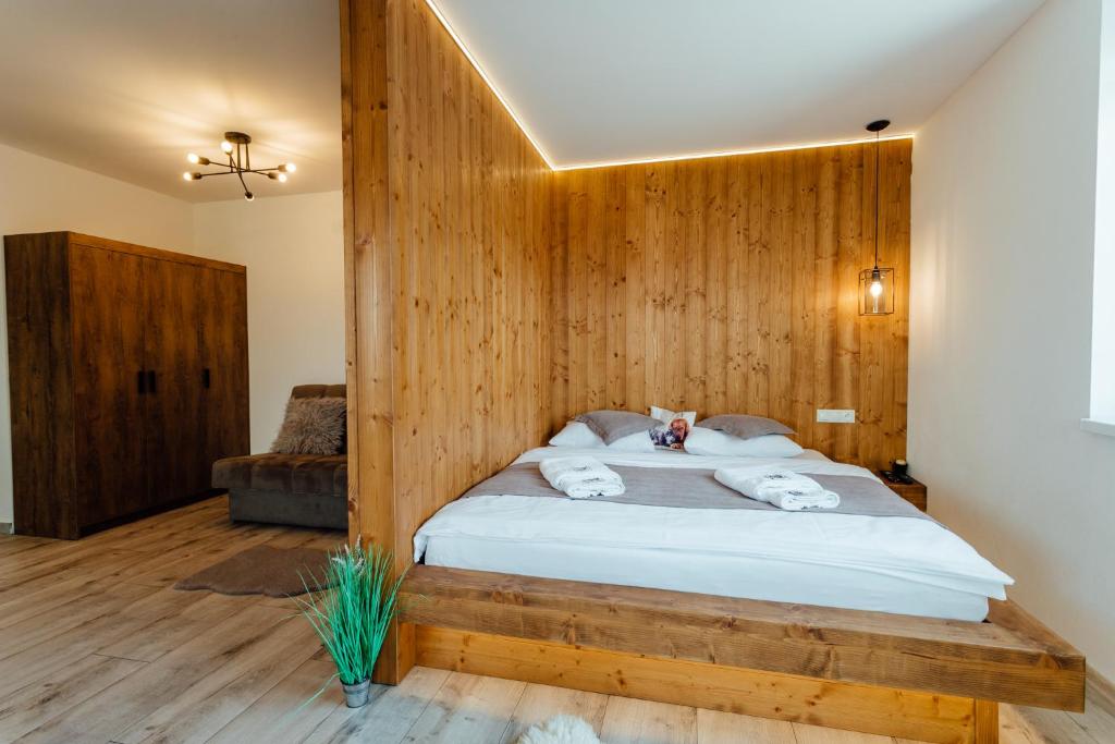 a bedroom with a bed with a wooden wall at Miracle Seasons in Liptovský Mikuláš