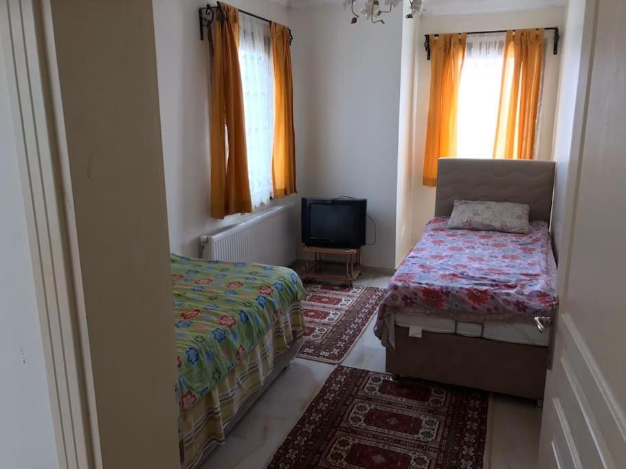 een kleine kamer met 2 bedden en een televisie bij Sivas Sıcak Çermik Kaplıca Villa 