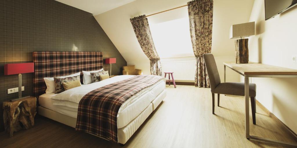 a bedroom with a bed and a desk and a window at Weingut Hees - Landgasthof Zum Jäger aus Kurpfalz in Auen