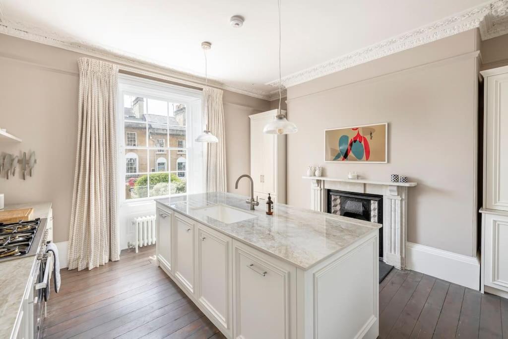 a kitchen with white cabinets and a fireplace at Dunsford House - Elegant Townhouse with Parking in Bath