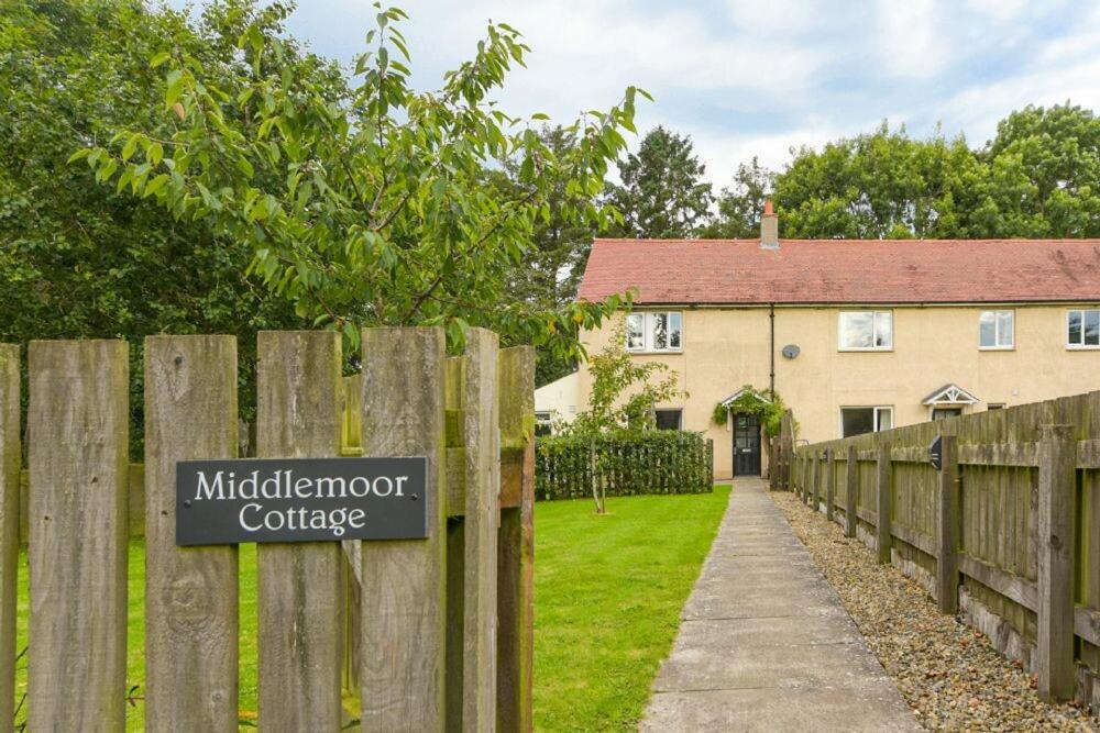 a sign on a wooden fence in front of a house at Middlemoor Cottage in Alnwick