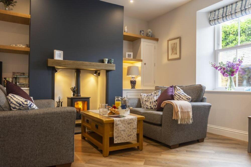 a living room with two couches and a fireplace at Wisteria Cottage in Warkworth